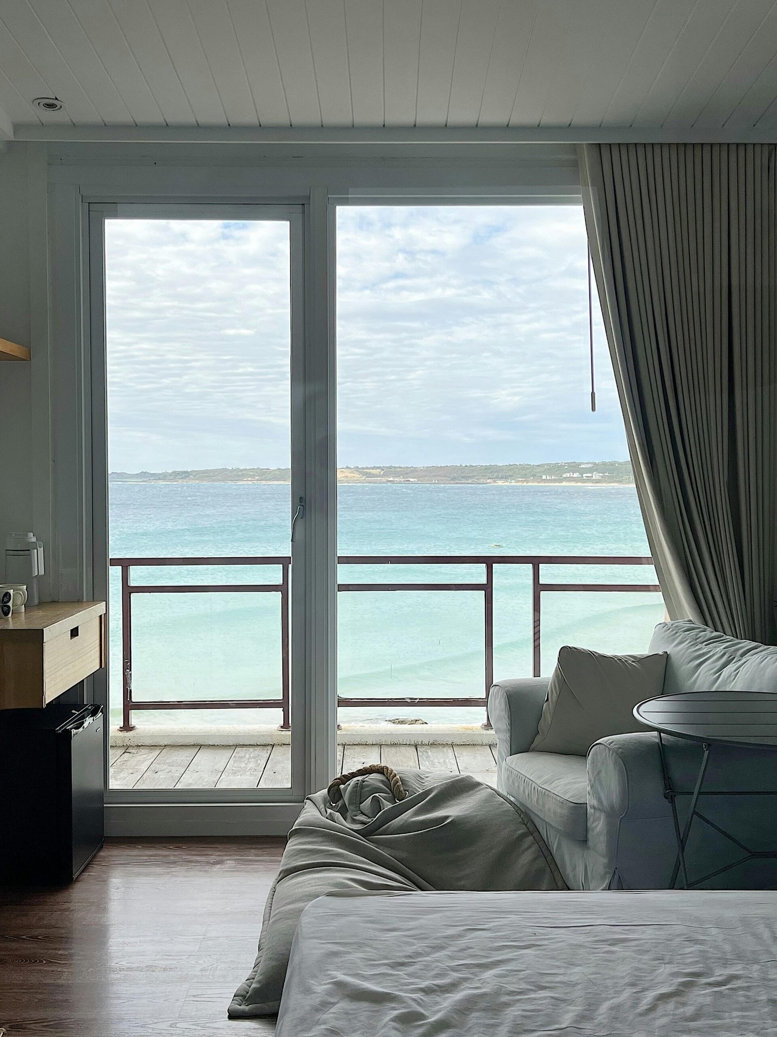 Modern bedroom with a view of the ocean through a large window, perfect for relaxation.